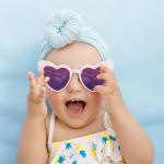 Baby wearing a turban and heart sunglasses on a blue background.