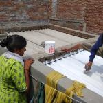 Residents of an informal settlement in India’s Ahmedabad city work on painting their home with sun-reflective white paint