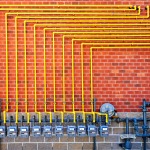 row of residential gas meters on a brick wall