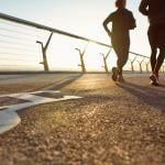 Two people running on the bridge in the morning with a view of sunrise.