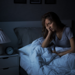 Woman sitting in bed in the dark unable to sleep