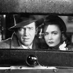 James Stewart and Donna Reed look out of the back window of vintage car in a scene from the movie 'It's A Wonderful Life.'