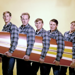 Rock and roll band "The Beach Boys" pose for a portrait with a surfboard in August 1962 in Los Angeles, California. (L-R) Brian Wilson, Mike Love, Dennis Wilson, Carl Wilson, David Marks. 