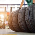 A worker gets a hold of four tires inside a car service establishment.