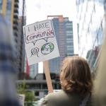 A demonstrator holds a sign that reads "I hate commuting" as Amazon employees and supporters gather during a protest against recent layoffs, a return-to-office mandate, and the company's environmental impact.