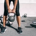 A person lifting a kettlebell weight at an outdoor gym.