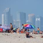 People relaxing on the beach with the skyline of downtown Miami behind them.