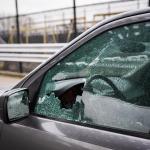 A close-up image of a driver's seat window showing damaged glass from car theft.
