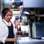 Three young workers in a coffee shop training to become baristas.