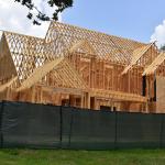 A green fence surrounds the wooden structure of a new home being built in Houston, Texas.