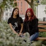 Genesis Callero, 18, and sister Karen Callero, 17, pose for a portrait on a bench surrounded by plants in New York. 