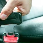 A person's hand inserting the seatbelt clip into the buckle.