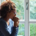 Woman sitting by a window looking worried