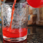Red drink pouring into a glass
