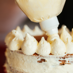 White icing being piped on a cake