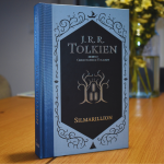 A hardcover copy of the book 'The Silmarillion' by J.R.R Tolkien on a wooden table