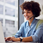Telemarketer in a blue shirt smiles while on a call.