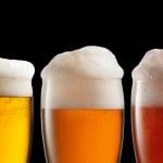 Three glasses of beer of different kinds on a black background.