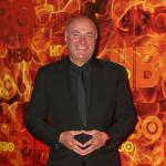 Kevin O'Leary poses in front of a red and orange HBO step-and-repeat background.