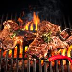 T-bone steak cuts being grilled in open fire.