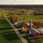 Overhead view of a rural farm with barns, storage silos and green fields