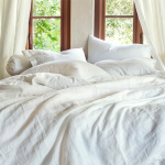 A queen size bed laid cozily with white linen sheets.