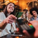 Group of women on a night out while one of them pays with a credit card.