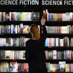 A person browses a big selection of sci-fi books at the store.