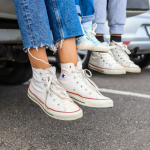 Cropped legs of an adult, teenager and toddler sitting together on the back of a car wearing sneakers