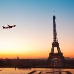 View of the Eiffel Tower during sunset with a plane seen flying over.