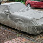 A car covered by a grey tarpaulin.