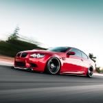 Red BMW driving on road with motion blur in background.