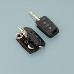 Broken damaged car key gob and new remote vehicle key side by side against pale greenish grey background.  