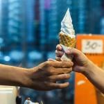 Worker hands customer soft serve ice cream cone.