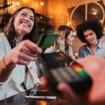 A group of young women dining out and one of them pays with a credit card.