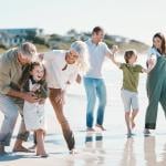 Big family with grandparents play and laught at the beach.