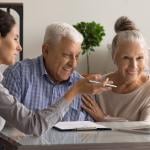 An elderly couple happily engaged in a mortgage meeting with a banking specialist.