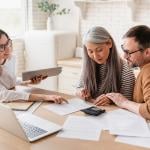 A couple consults with a finance professional while looking at a set of documents.