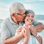 Happy retired couple embrace on the beach.