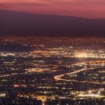 Panoramic night view of urban sprawl in San Jose, Silicon Valley, California; Visible light trail left by cars driving on one of the freeways.