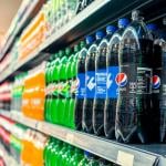 A row of soda products on display at an aisle in a supermarket