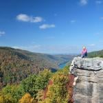 Scenic view of person in a pink shirt sitting on the Coopers Rock outlook in West Virginia.