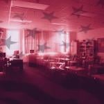 Photo illustration with red tones and American flag overlaid on silhouetted classroom; concept of changing education.