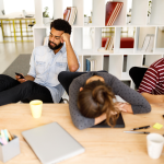 Three distracted young coworkers at a table.