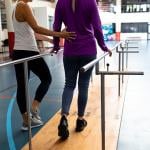 A female physical therapists assist a patient in a walking practice.