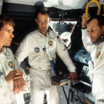 Kevin Bacon, Tom Hanks, and Bill Paxton talking in ship in a scene from the film 'Apollo 13', 1995.