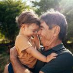 Grandparent spending time with grandchild in a park on a sunny day.