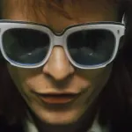 Close-up portrait of David Bowie wearing a pair of sunglasses