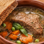 Crock pot with stewed meat and vegetables with a slice of bread