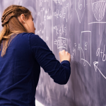 High school student working out a math problem on a classroom chalkboard